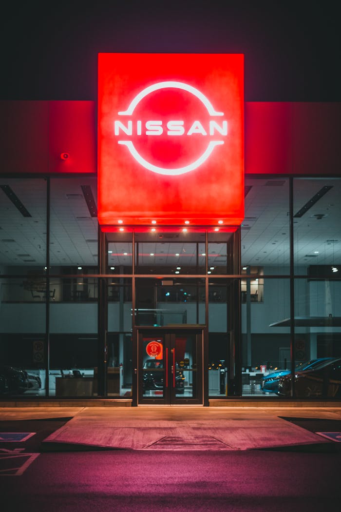 Services Facade of modern car showroom with glass wall and big shining red signboard in nighttime